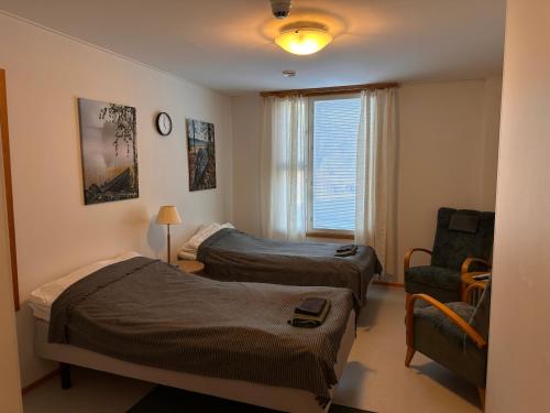 a room with two beds and a chair and a window at Enonkosken Kartano & Guesthouse in Enonkoski