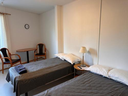 two beds in a room with a table and a chair at Enonkosken Kartano & Guesthouse in Enonkoski