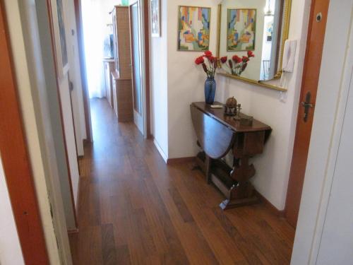 a hallway with a wooden floor and a table with flowers on it at Appartamento Pineta in Grado