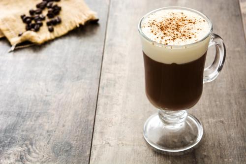 a glass cup of coffee on a wooden table at Hotell Iföhus in Bromölla