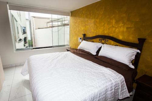 een slaapkamer met een groot bed met een gele muur bij Beautiful Penthouse in Lima, in front of the park in Lima