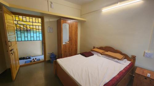 una piccola camera da letto con un letto e una finestra di Anand Nivas a Malwan