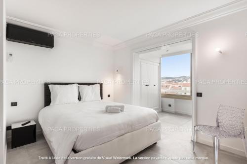 une chambre blanche avec un lit et une chaise dans l'établissement Cannes appart 3 chambres luxe - Impératrice, à Cannes