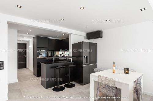 une cuisine avec des armoires noires et une table blanche dans l'établissement Cannes appart 3 chambres luxe - Impératrice, à Cannes