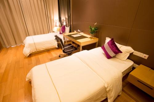 Habitación de hotel con 2 camas y escritorio en SLD-Yicen INTERNATIONAL SERVICE APARTMENT, en Guangzhou