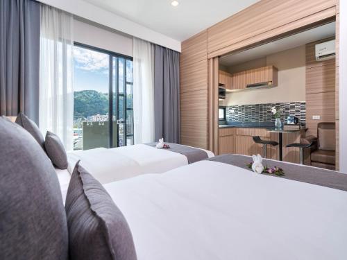 two beds in a hotel room with a large window at Patong Bay Residence in Patong Beach