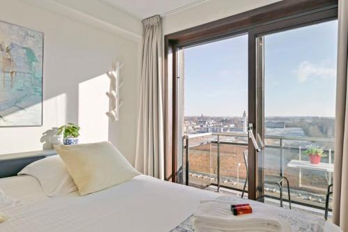 een slaapkamer met een bed en een groot raam bij Sunny and comfortable 2 bedroom appartement with stunning Sea-view and 2 terraces in Knokke-Heist