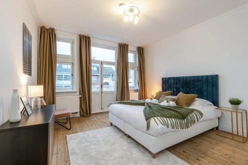 a bedroom with a bed and a desk and windows at Authentic townhouse near the beach of Blankenberge in Blankenberge