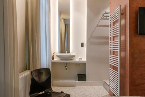 a bathroom with a black chair and a sink at WAY SWEET DREAMS - Room 2 in Ghent