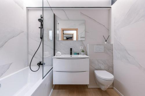 een witte badkamer met een wastafel en een toilet bij Appartement in 'De Haan' in De Haan