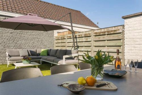 a table with an umbrella and some fruit on it at Huswell - Summer-house with sunny garden nearby beach in Knokke-Heist