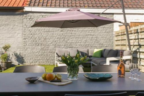 a table with an umbrella and some fruit on it at Huswell - Summer-house with sunny garden nearby beach in Knokke-Heist