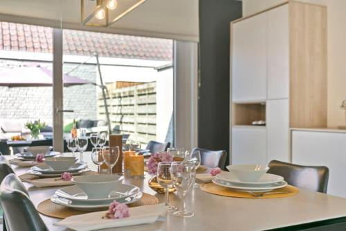 a table with plates and glasses on a table at Huswell - Summer-house with sunny garden nearby beach in Knokke-Heist