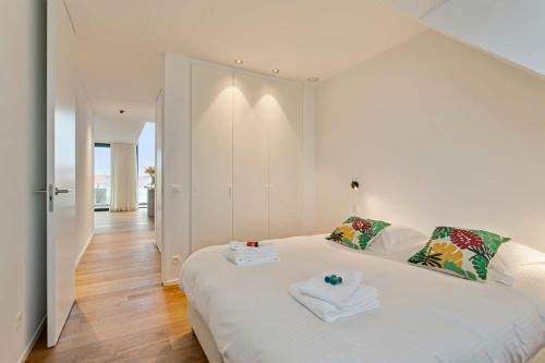 ein Schlafzimmer mit einem weißen Bett und Handtüchern darauf in der Unterkunft Majestic new penthouse with 2 parkings in Knokke-Heist