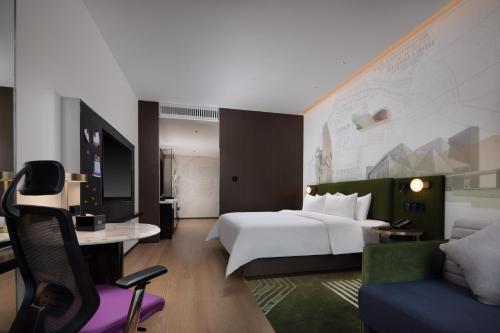 深セン市にあるHampton by Hilton Shenzhen Nanshan Science and Technology Parkの白いベッドとデスクが備わるホテルルームです。