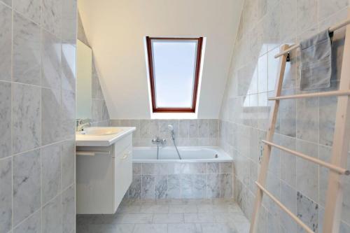 een badkamer met een wastafel en een bad bij Warm Lofty and Spacious Studio in De Haan
