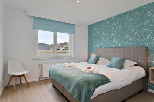 a bedroom with a large bed with a blue wall at Bright and spacious bungalow with garden near the beach in Middelkerke