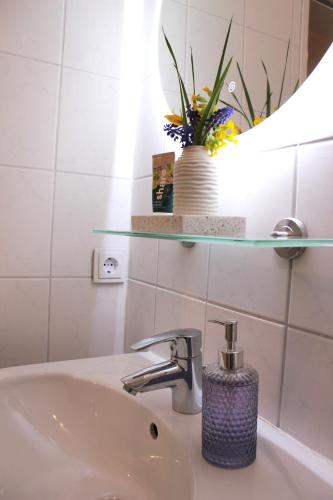 a bathroom sink with a mirror and a vase with flowers at Blaues Paradies in Bad Rodach