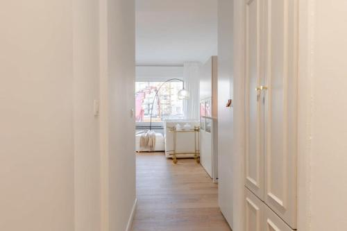 een hal met witte muren en een houten vloer bij Stylish apartment with cosy fireplace near the sea in Knokke-Heist