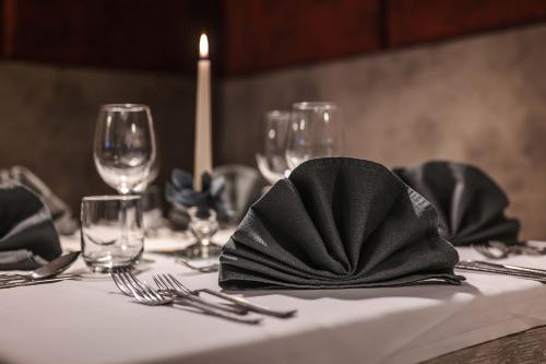 uma mesa com uma toalha de mesa branca com um guardanapo preto em Hotel Tannenhof em Brunico