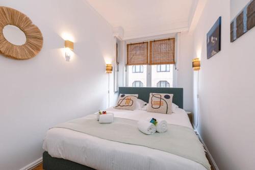 a bedroom with a large white bed with two pillows at Huswell - Comfy Apartment with Side Seaview and 2 free bikes in Knokke-Heist