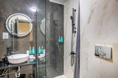 a bathroom with a shower with a sink and a mirror at Hotel Forty One in Bucharest