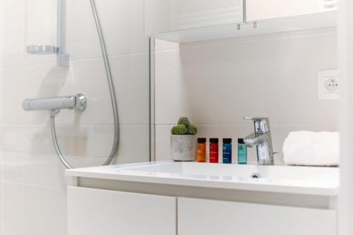 a white bathroom with a sink and a shower at Bright apartment only 5 minutes from the beach in Middelkerke