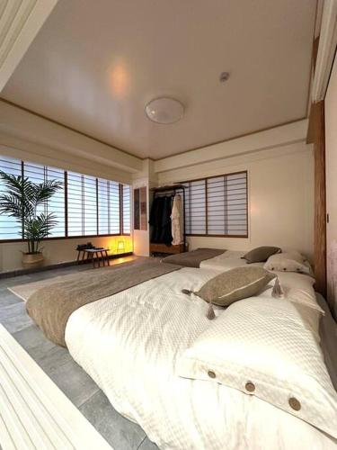 a large bedroom with a large white bed with windows at Kyo Sai 浅草3F　120㎡超え浅草寺まで徒步約10分 in Tokyo