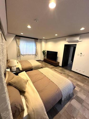 a bedroom with two beds and a flat screen tv at Kyo Sai 浅草3F　120㎡超え浅草寺まで徒步約10分 in Tokyo