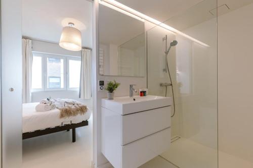 a white bathroom with a sink and a shower at Pleasant Apartment for Families close to the beach in De Haan