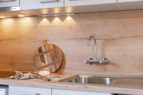 a kitchen with a sink and a wooden wall at Charming studio with terrace nearby the beach in Middelkerke