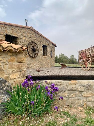 a stone building with some flowers in front of it at Masia La Casablanca in La Puebla de Valverde