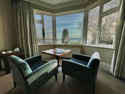 a living room with two chairs and a table and windows at St Kyrans Guest House in Virginia