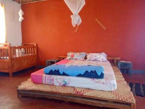 ein Schlafzimmer mit einem Bett mit orangefarbenen Wänden in der Unterkunft Ecolodge d'Isalo in Ranohira