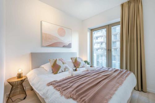 Huswell - Apartment with terrace close to the sea في أوستند: غرفة نوم بيضاء مع سرير كبير ونافذة