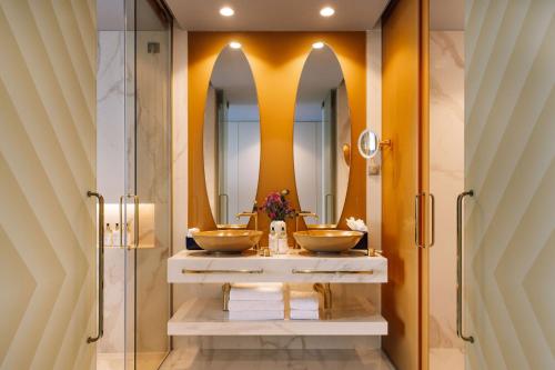 a bathroom with two sinks and two mirrors at The Reserve - The Leading Hotels of the World - Savoy Signature in Funchal