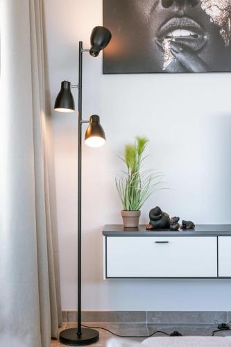 a black floor lamp next to a table with a plant at Huswell - Bright apartment with seaview in Bredene