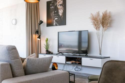 a living room with a flat screen tv on a white cabinet at Huswell - Bright apartment with seaview in Bredene