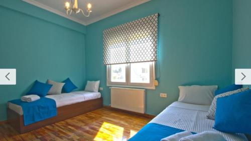 een blauwe kamer met een bed en een raam bij Cosy Colorful House in Kavala