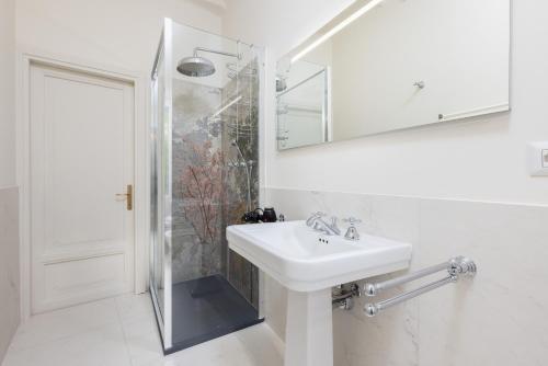 a white bathroom with a sink and a shower at Living UniQC Apartment - Duomo in Milan