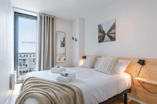 a white bedroom with a large bed with towels on it at Cosy apartment with frontal seaview in Nieuwpoort