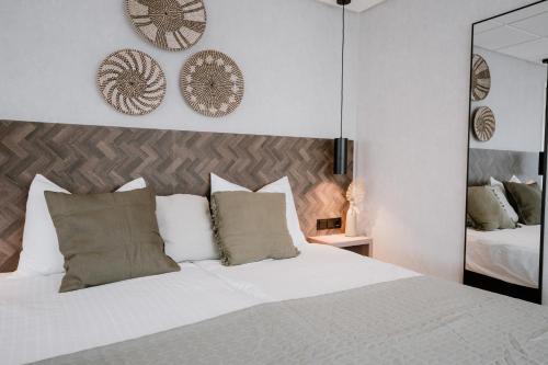 a bedroom with a white bed with pillows and a mirror at Kodde Studio in Aagtekerke