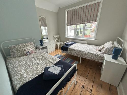 Habitación pequeña con 2 camas y ventana en Downs Gate Cottage, en Eastbourne