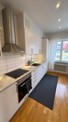 cocina con armarios blancos y fogones negros en Luxurious And Spacious Apartment, en Gotemburgo