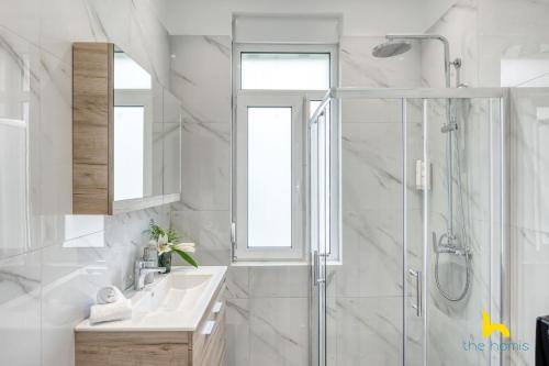 a white bathroom with a sink and a shower at Contemporary 2-BDR APT near Kalimarmaro & Alsos Park! in Athens