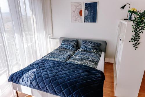 a bed with a blue comforter in a bedroom at Cosy apartment Zugló next to Puskás Aréna in Budapest