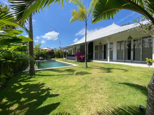 ein Haus mit einem Pool und Palmen in der Unterkunft Vicolo ArtVillas in Uluwatu