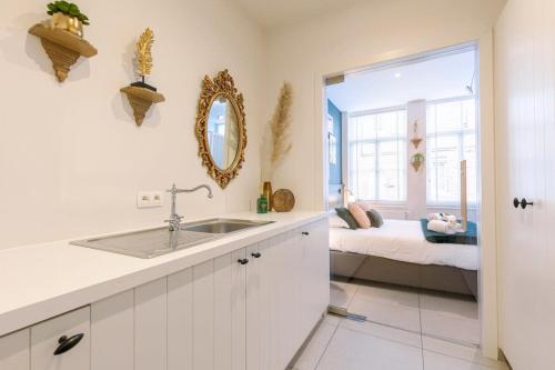 a white kitchen with a sink and a bedroom at Huswell - Stylish studio in the heart of Bruges in Bruges