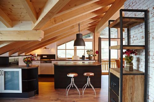 eine Küche mit einer schwarzen Insel und Hockern in der Unterkunft Alpenlodge Charivari - SommerBergBahn unlimited kostenlos in Oberstdorf