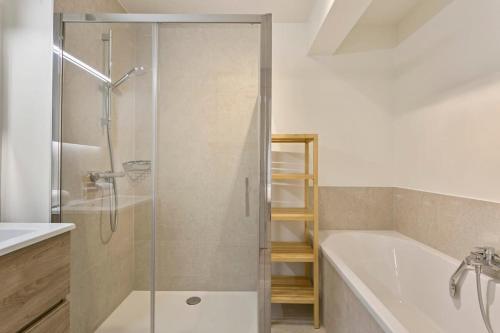 ein Badezimmer mit einer Dusche, einer Badewanne und einem Waschbecken in der Unterkunft Majestic Apartment With Breathtaking Sea View in De Haan
